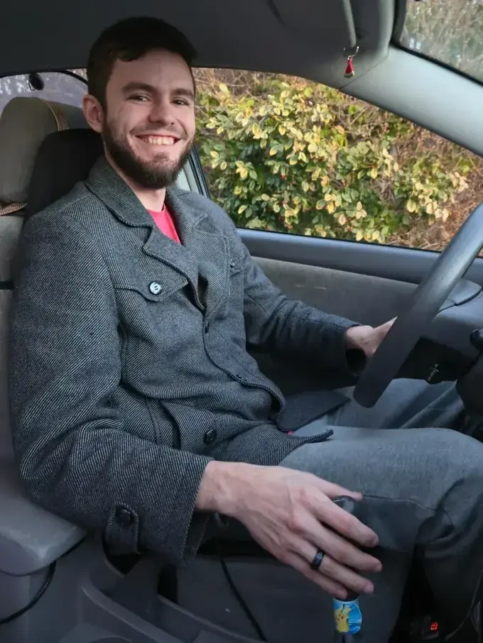Brendan in the driver's seat of his 2006 Toyota Corolla with 271,000 miles, still maintained by hand