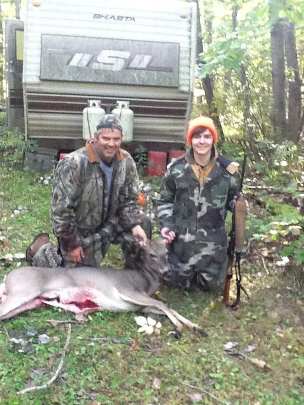 Brendan and his dad posing with a deer after a successful rifle season hunt in rural Michigan